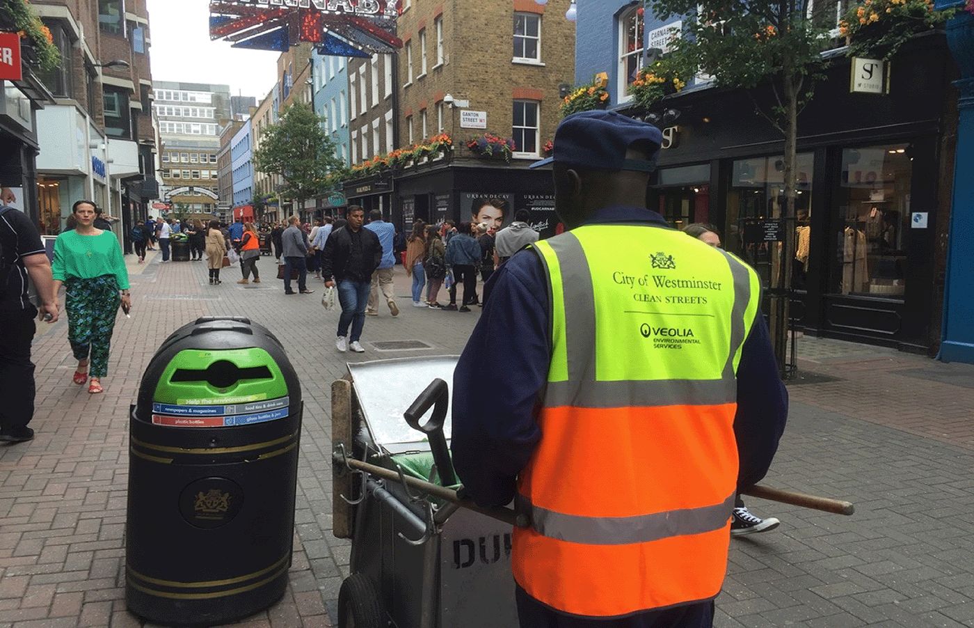 Cleaning operative at work on a busy retail street